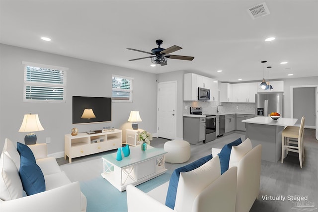 living room featuring sink, ceiling fan, and light hardwood / wood-style flooring