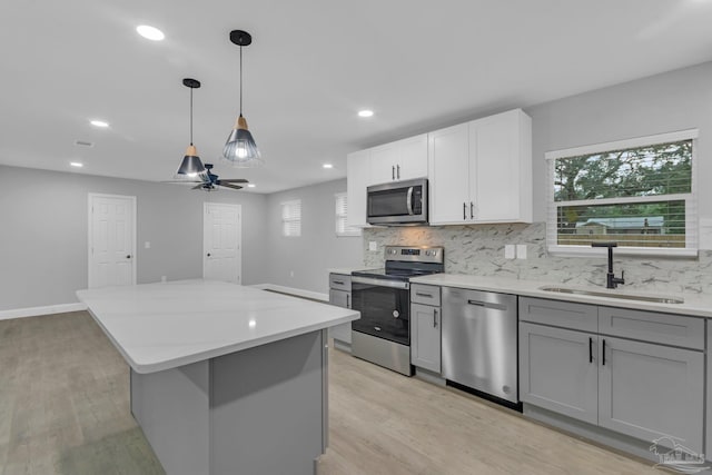 kitchen with light hardwood / wood-style floors, sink, appliances with stainless steel finishes, decorative light fixtures, and gray cabinets