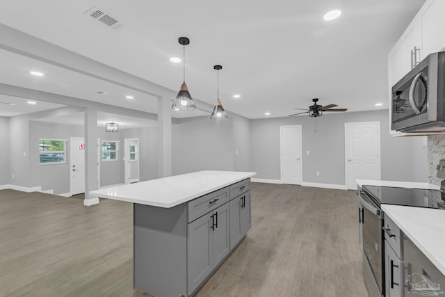 kitchen with gray cabinetry, light wood-type flooring, appliances with stainless steel finishes, pendant lighting, and white cabinets