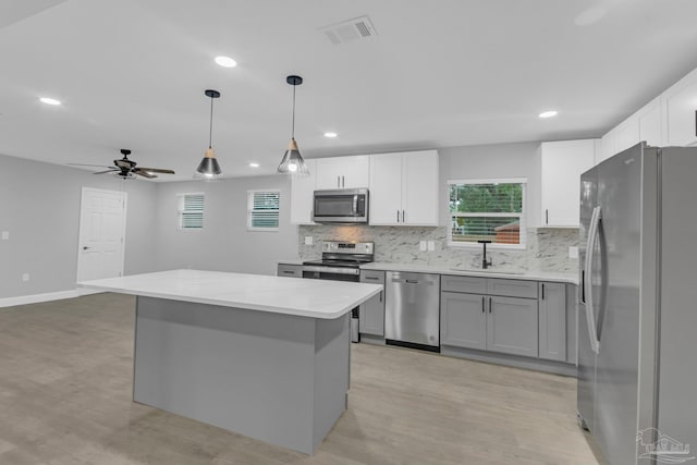 kitchen featuring stainless steel appliances, sink, light hardwood / wood-style flooring, a center island, and pendant lighting