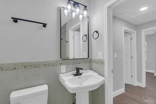 bathroom with toilet, sink, tile walls, and hardwood / wood-style floors