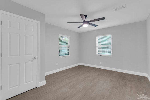 empty room with a wealth of natural light, ceiling fan, and light wood-type flooring