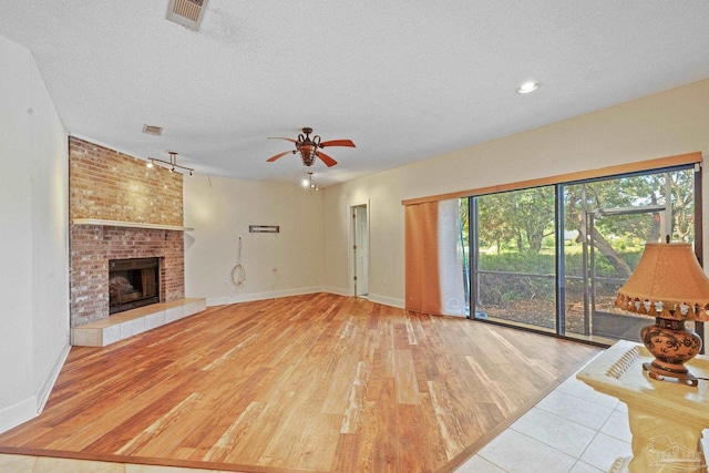 2715 Masters Blvd, Navarre, FL 32566 - unfurnished living room featuring a textured ceiling, a ceiling fan, wood finished floors, a fireplace, and rail lighting