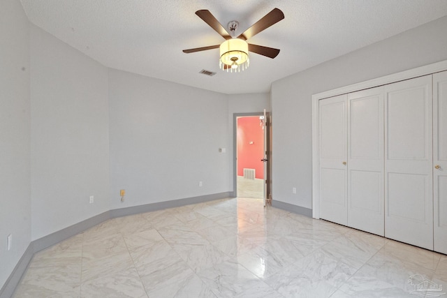 unfurnished bedroom featuring a textured ceiling, ceiling fan, and a closet