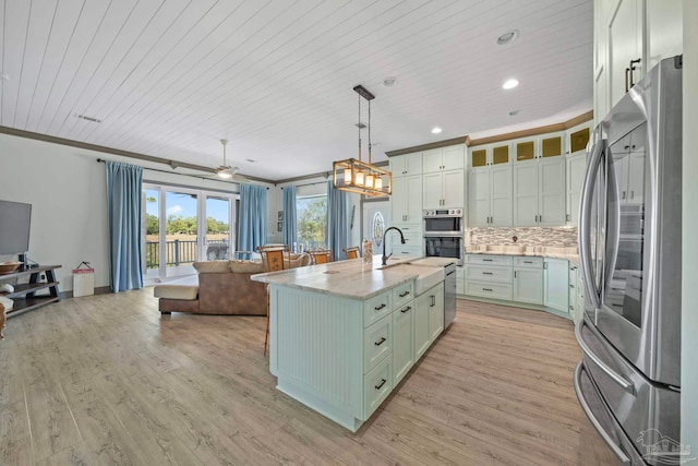 7730 Sunfish Ln, Milton, FL 32583 - kitchen with appliances with stainless steel finishes, open floor plan, light wood-style flooring, a kitchen island with sink, and decorative backsplash