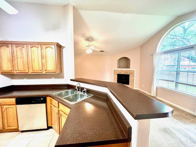 kitchen with vaulted ceiling, a wealth of natural light, a tile fireplace, dishwasher, and ceiling fan