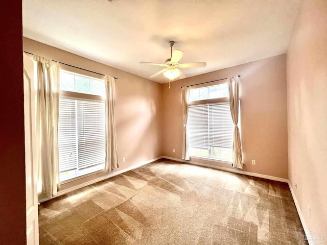 carpeted empty room with ceiling fan and plenty of natural light