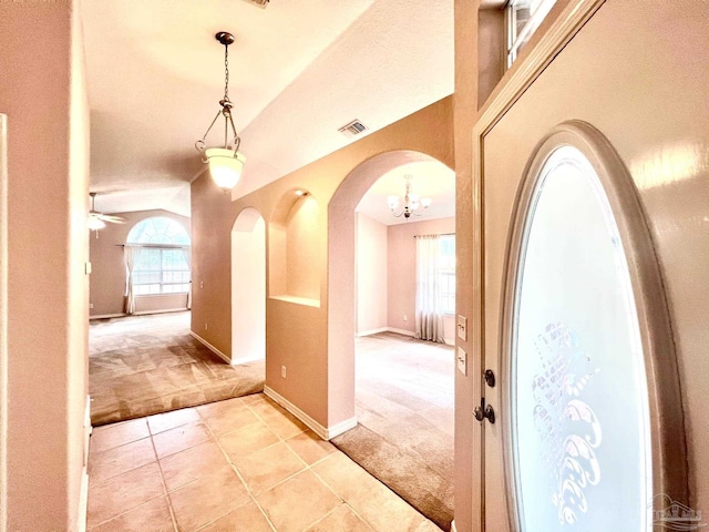 corridor with light carpet, an inviting chandelier, and lofted ceiling