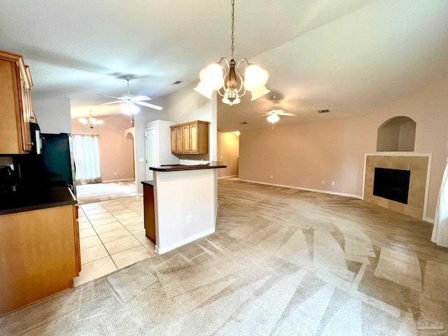 kitchen featuring a fireplace, light carpet, and ceiling fan with notable chandelier