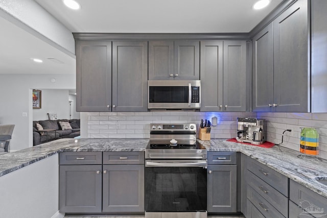 kitchen with backsplash, gray cabinets, and appliances with stainless steel finishes