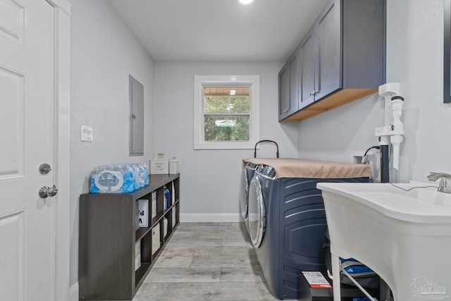 laundry room with sink, cabinets, light hardwood / wood-style flooring, electric panel, and washer and clothes dryer