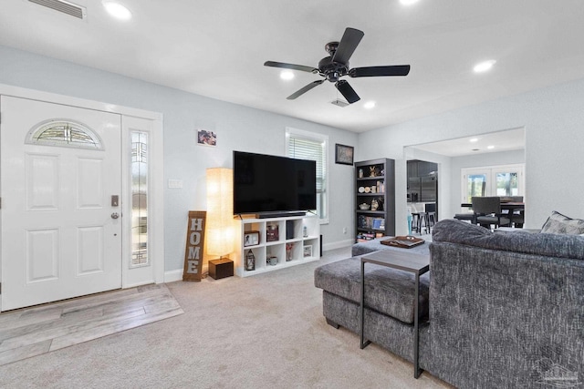 living room featuring ceiling fan, light carpet, and a wealth of natural light