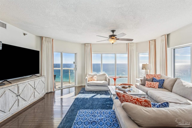 living area with a ceiling fan, a textured ceiling, visible vents, and hardwood / wood-style flooring
