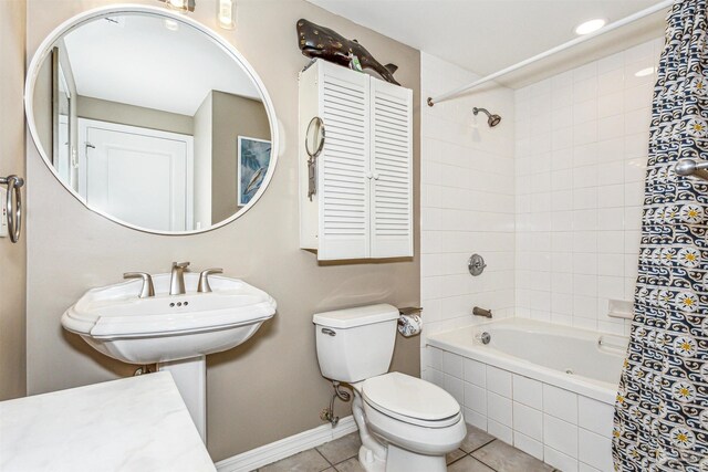 bathroom with tile patterned flooring, toilet, baseboards, washtub / shower combination, and a sink