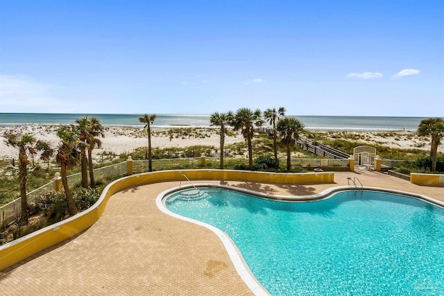 community pool with a view of the beach and a water view
