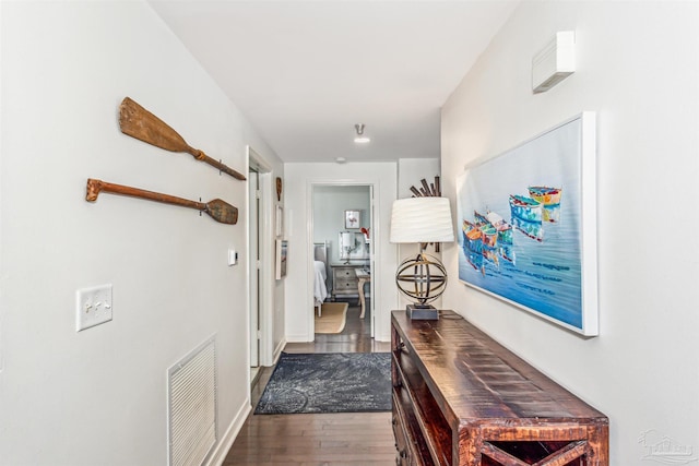 corridor with visible vents, dark wood finished floors, and baseboards