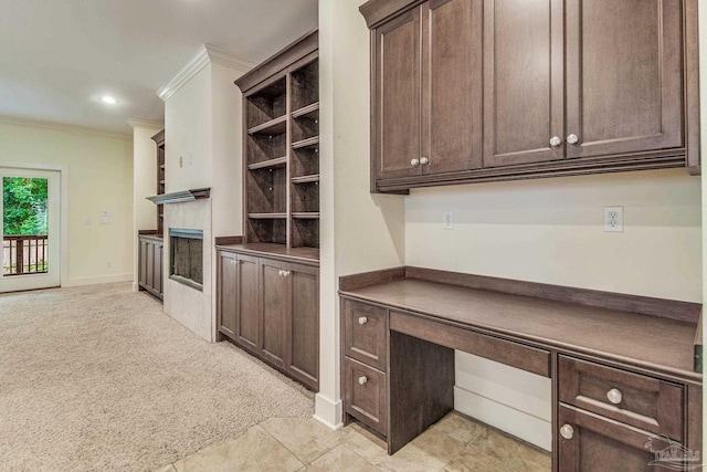 kitchen featuring dark brown cabinetry, light colored carpet, and crown molding