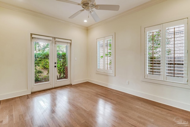 empty room featuring ceiling fan, plenty of natural light, crown molding, and light wood-type flooring