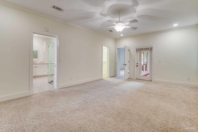 spare room with ceiling fan, crown molding, and light carpet