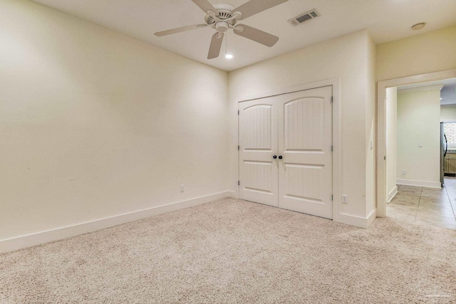 unfurnished bedroom with ceiling fan, light carpet, and a closet