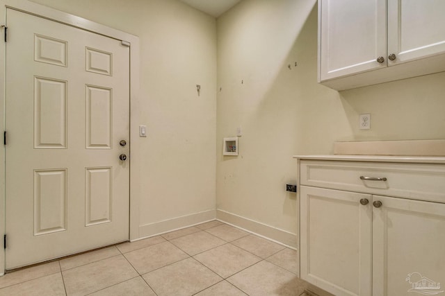 laundry area with hookup for a washing machine, light tile patterned floors, and cabinets