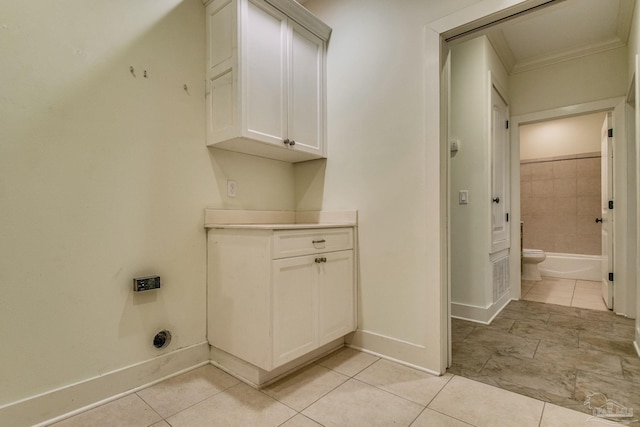 clothes washing area featuring light tile patterned floors and crown molding