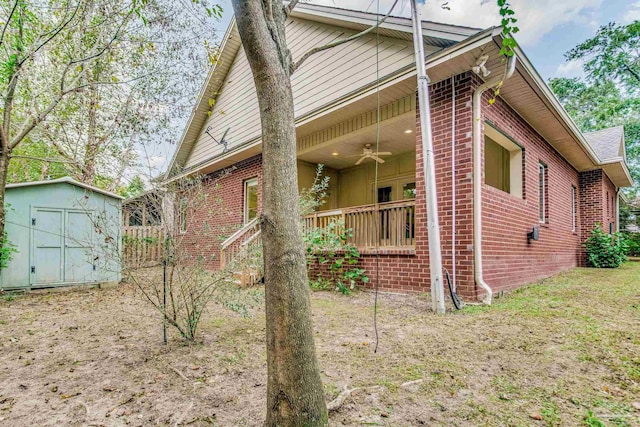 view of side of home with ceiling fan and a storage shed