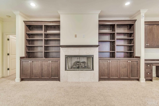 unfurnished living room with crown molding, light carpet, and a tiled fireplace