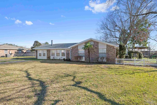 view of front of house with brick siding, fence, and a front lawn