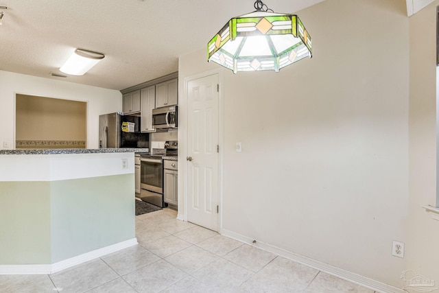 kitchen featuring light tile patterned floors, a textured ceiling, stainless steel appliances, and gray cabinetry