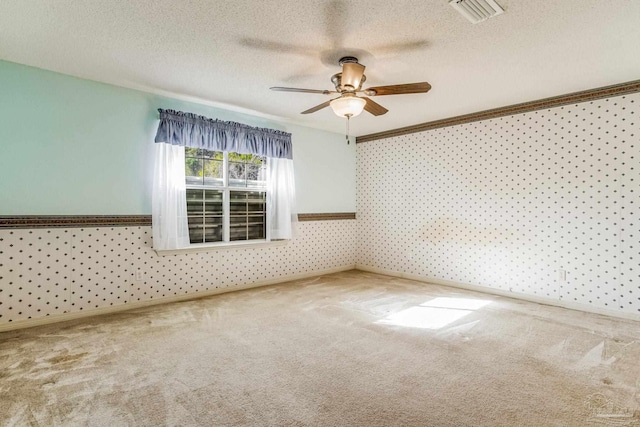 spare room with a textured ceiling, carpet floors, ceiling fan, and crown molding