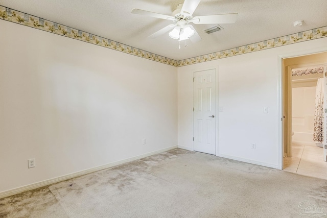 carpeted spare room featuring ceiling fan and a textured ceiling