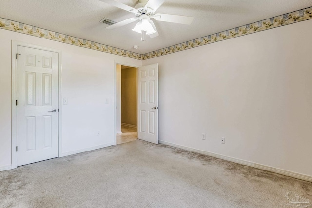 empty room featuring ceiling fan, a textured ceiling, and light carpet