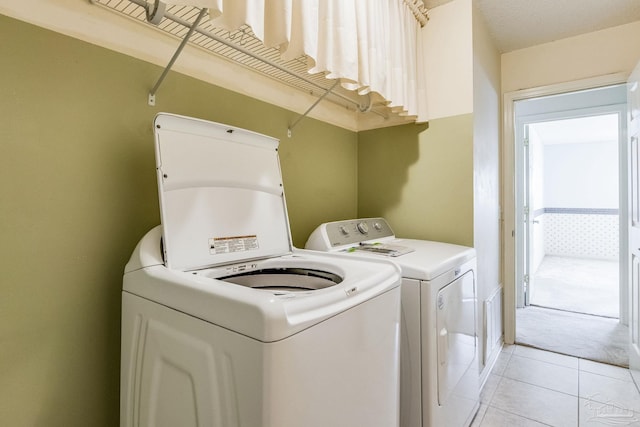 laundry room with independent washer and dryer and light tile patterned floors