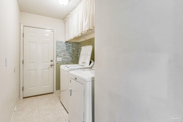 clothes washing area with light tile patterned floors, cabinets, a textured ceiling, and independent washer and dryer