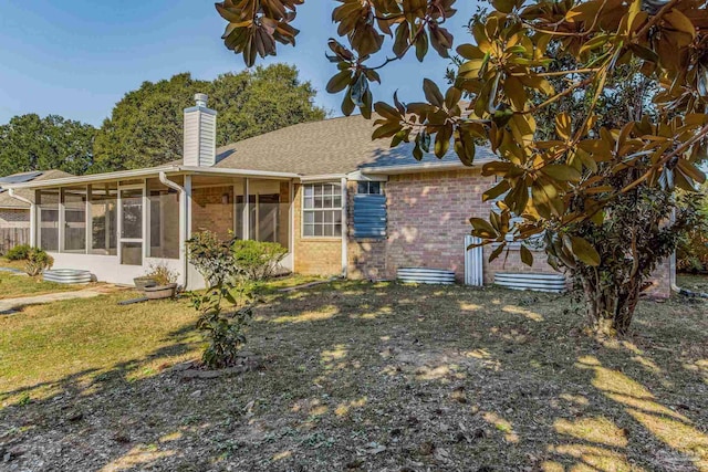 rear view of property with a lawn and a sunroom