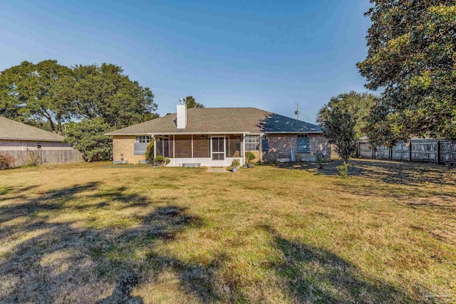 rear view of property featuring a lawn and a sunroom