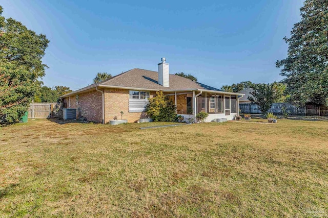 back of property with central air condition unit, a lawn, and a sunroom