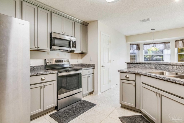 kitchen featuring appliances with stainless steel finishes, a textured ceiling, light tile patterned floors, and gray cabinetry