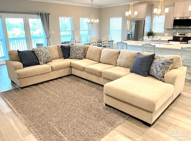 living room featuring crown molding, light wood-type flooring, and a notable chandelier