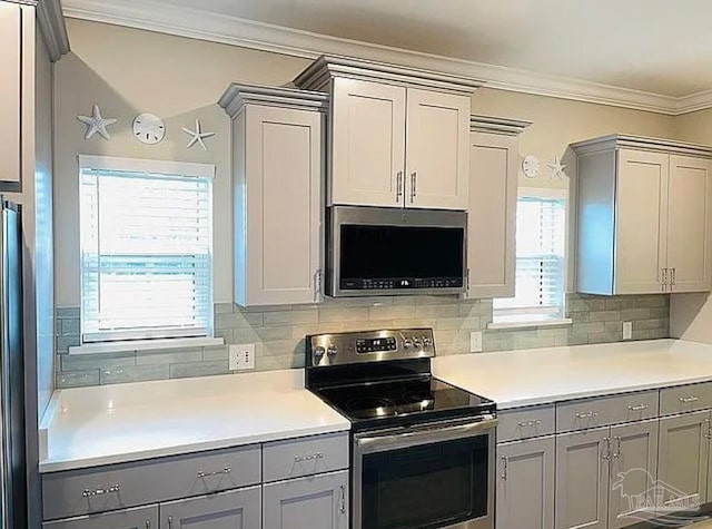 kitchen featuring tasteful backsplash, gray cabinets, crown molding, and appliances with stainless steel finishes