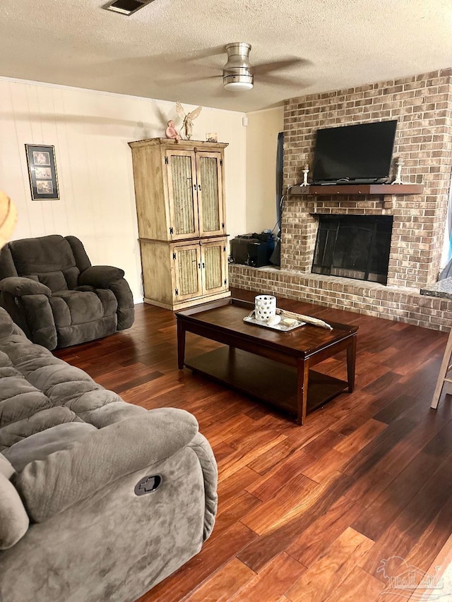 living room featuring ceiling fan, hardwood / wood-style floors, a textured ceiling, and a fireplace