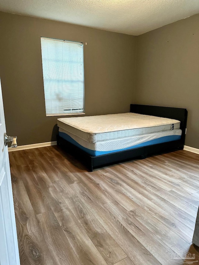 unfurnished bedroom with hardwood / wood-style flooring and a textured ceiling