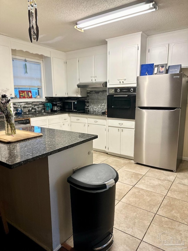 kitchen featuring light tile patterned floors, white cabinetry, dark stone countertops, black appliances, and decorative backsplash