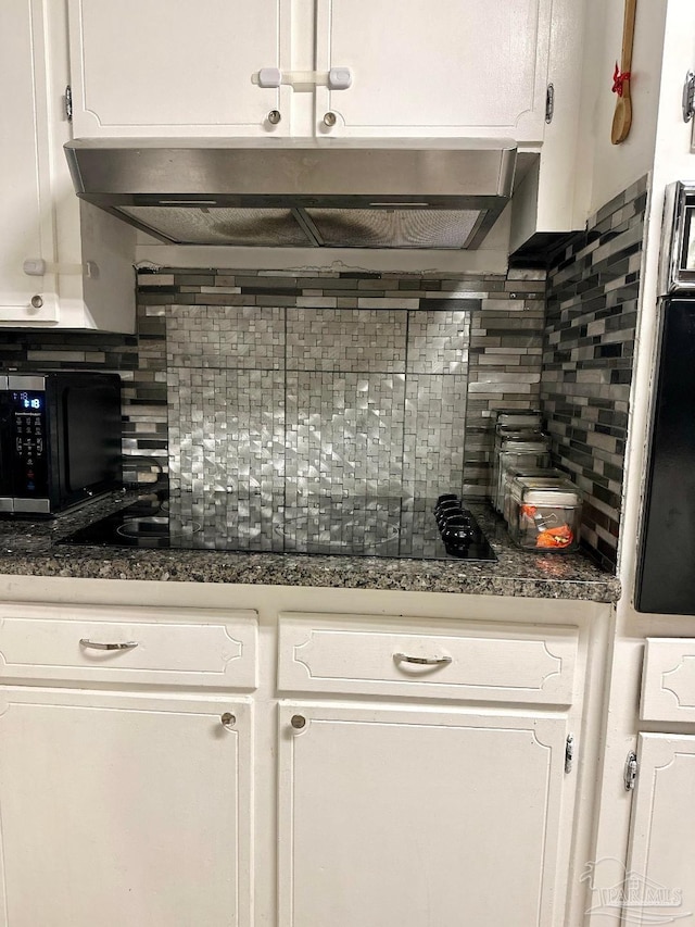 kitchen with dark stone countertops, decorative backsplash, and white cabinets