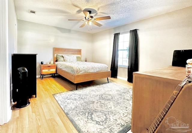 bedroom with hardwood / wood-style floors, a textured ceiling, and ceiling fan