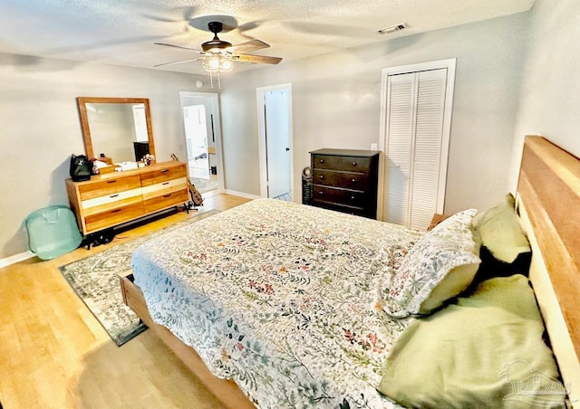 bedroom with hardwood / wood-style floors, ceiling fan, a textured ceiling, and a closet