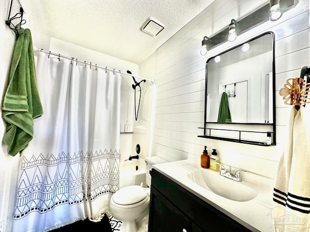 full bathroom with shower / bath combo, wood walls, vanity, toilet, and a textured ceiling