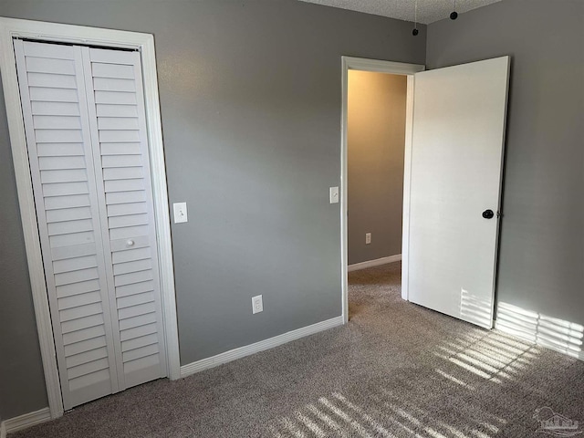 unfurnished bedroom featuring carpet flooring, a textured ceiling, and a closet