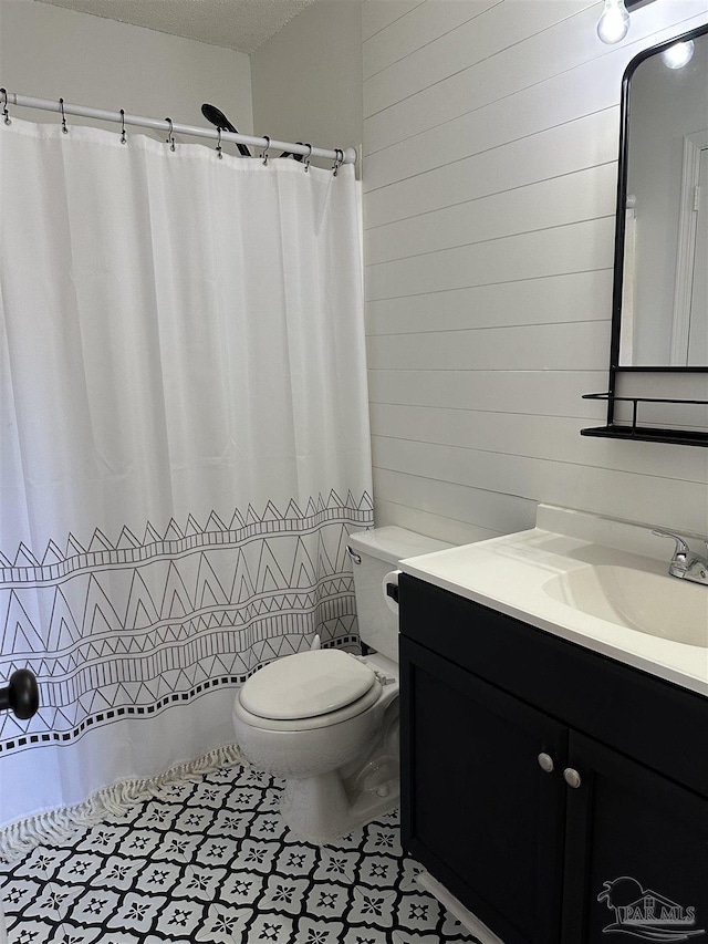 bathroom with wooden walls, vanity, a textured ceiling, and toilet